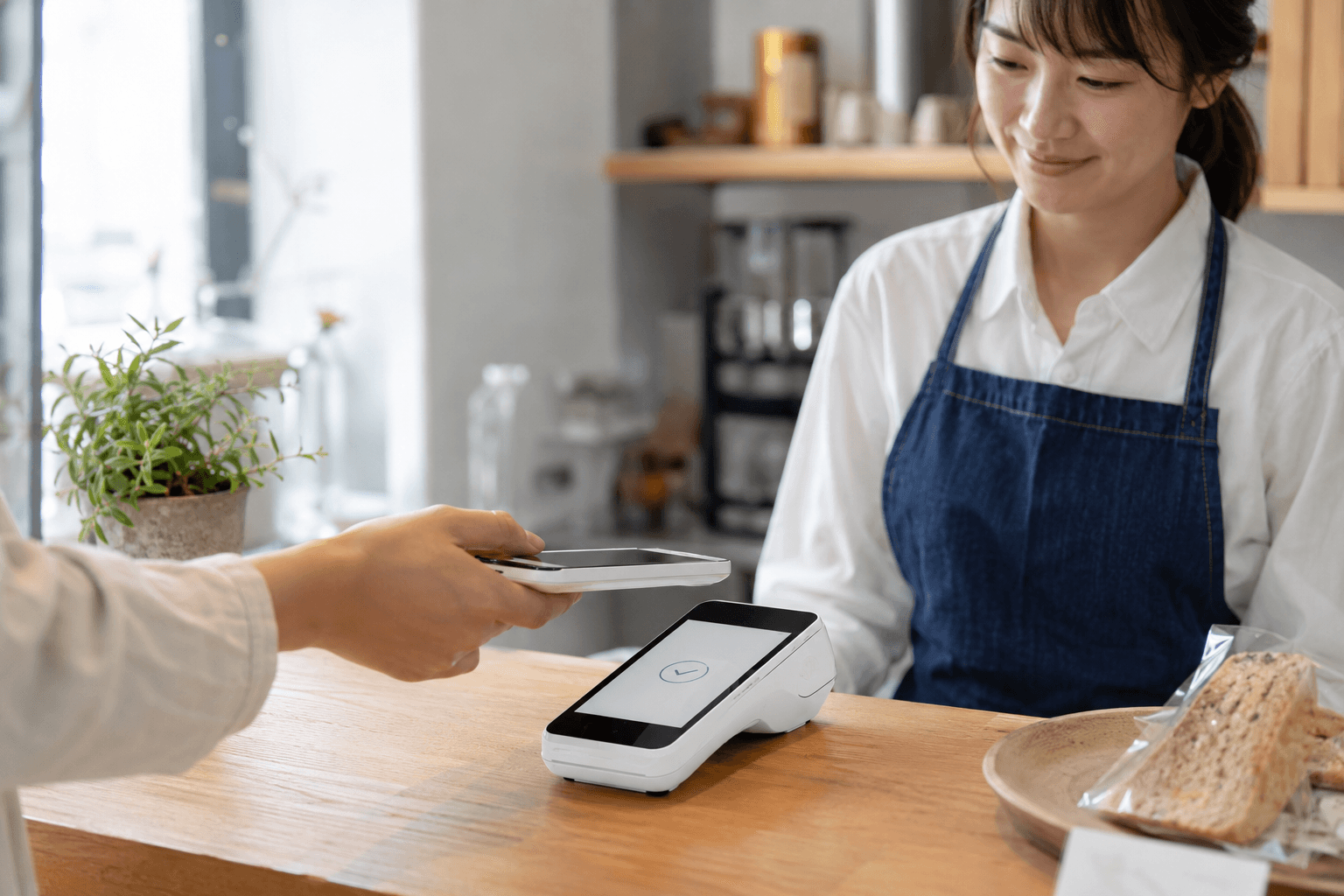 USEN PAYの決済端末でキャッシュレス決済を行う店舗スタッフとお客様