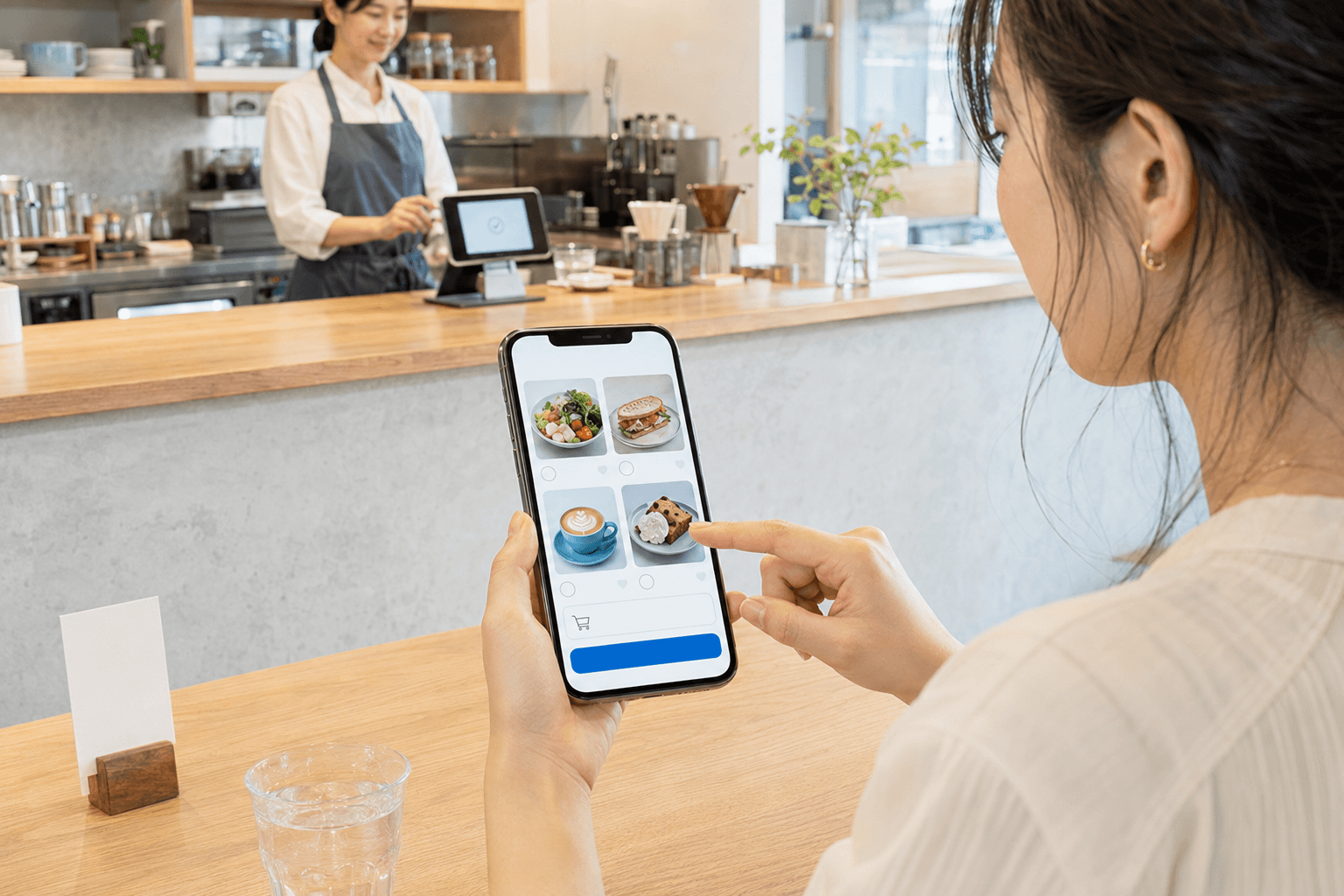 カフェでスマートフォンのモバイルオーダー画面から商品を選んでいる様子
