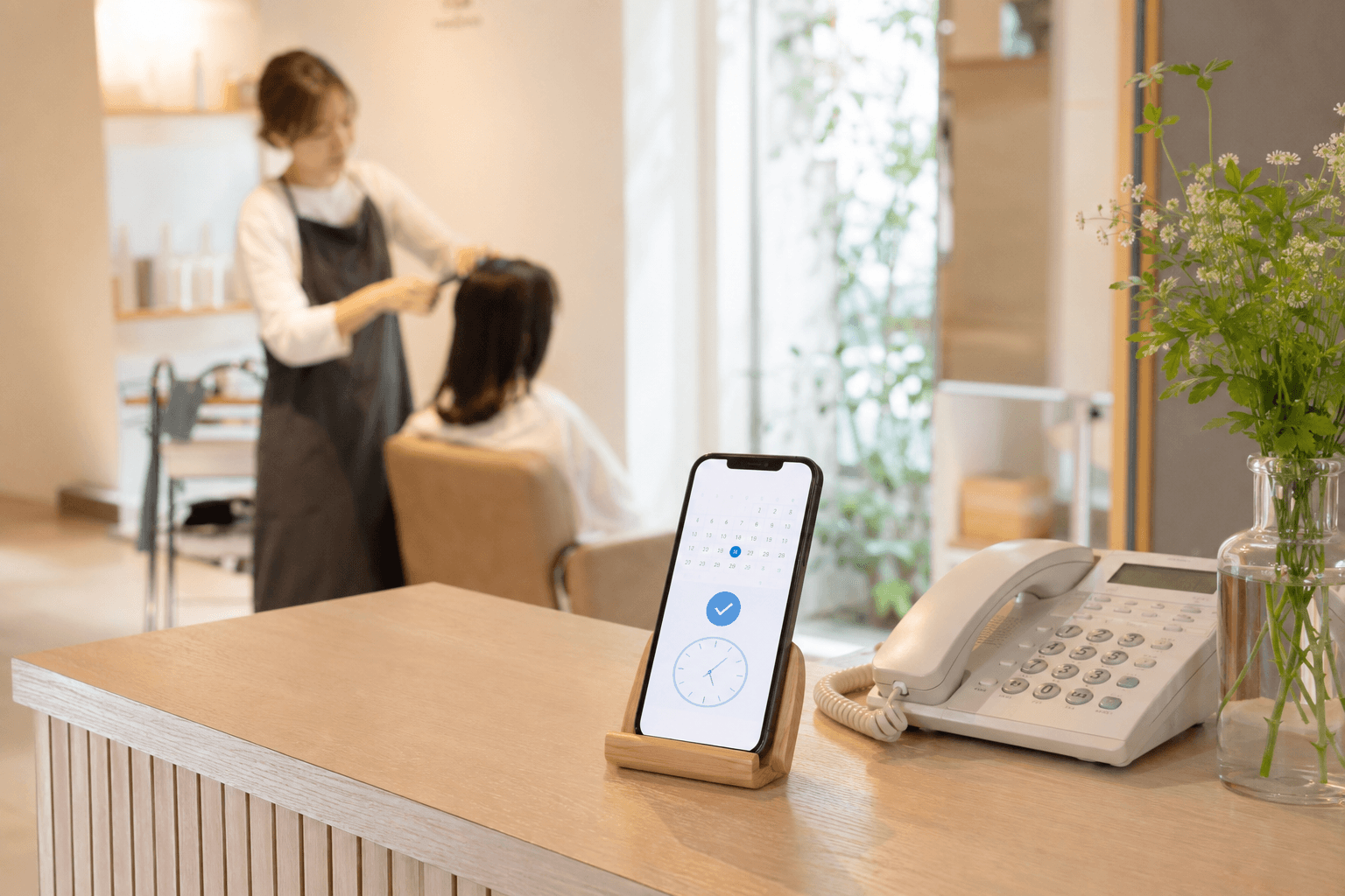 サロン受付でスマートフォンの予約画面を表示している様子